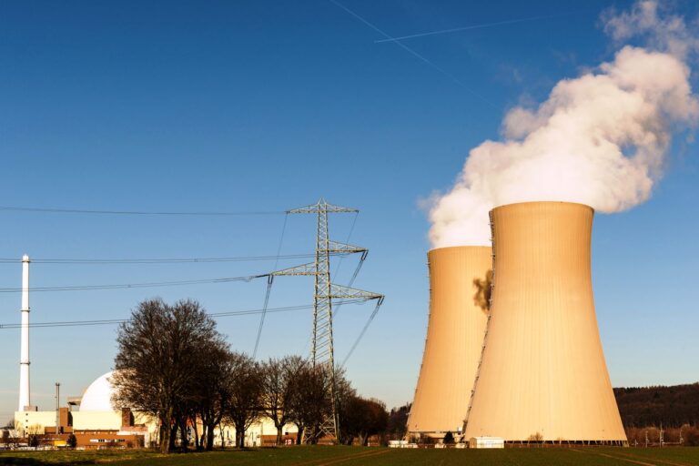 Chladicí věže jaderné elektrárny s oblakem páry nad krajinou