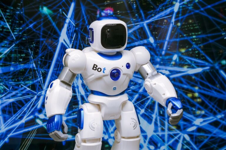 Bílý humanoidní robot s modře svítícími prvky na pozadí světel