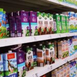 Krabice mléka s cenovkami v regálu supermarketu