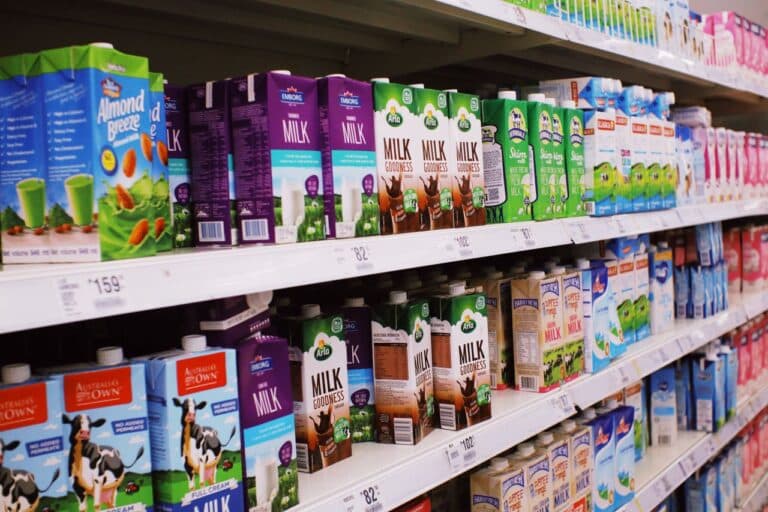 Krabice mléka s cenovkami v regálu supermarketu