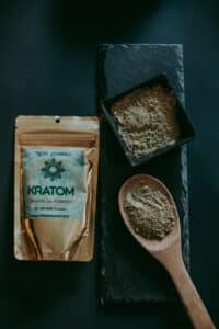 Kratomový prášek v misce a na dřevěné lžičce