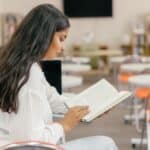 Studentka čte učebnici v prázdné učebně
