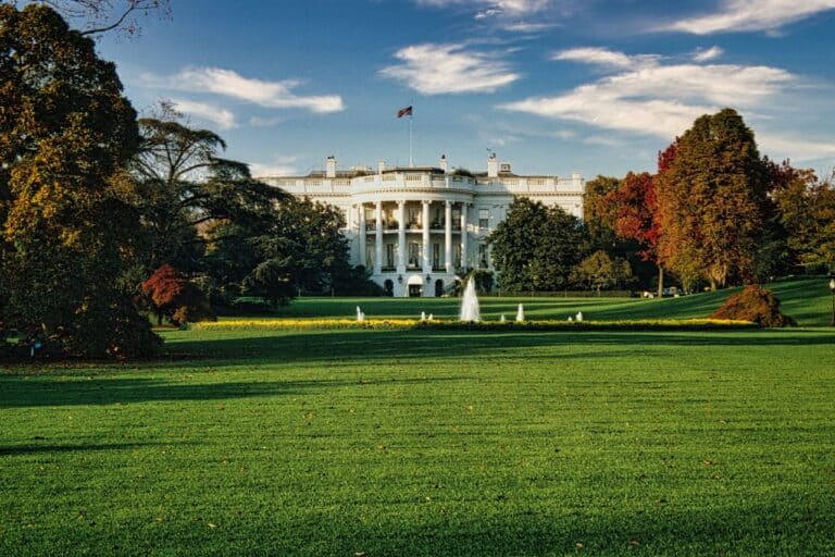 Bílý dům ve Washingtonu s fontánou na trávníku a podzimně zbarvenými stromy