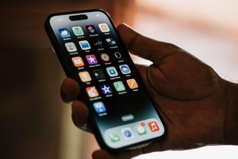 Detail ruky držící chytrý telefon, na displeji jsou zaostřené ikony aplikací