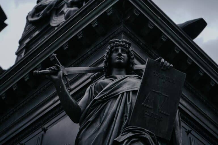 Kamenná socha spravedlnosti s váhami v jedné ruce a mečem v druhé