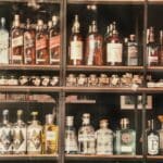 Police s lahvemi destilátů a likérů seřazenými ve vitríně prodejny s alkoholem