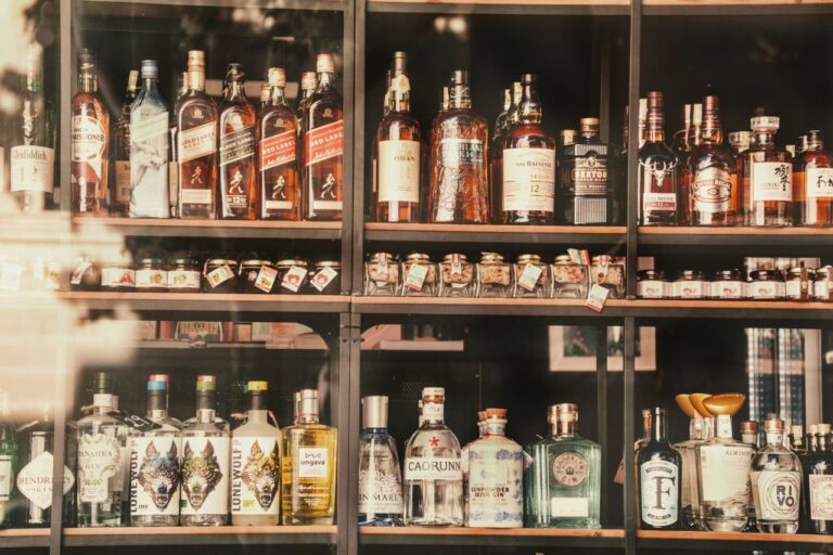 Police s lahvemi destilátů a likérů seřazenými ve vitríně prodejny s alkoholem