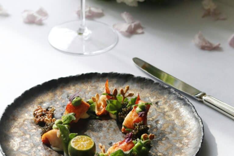 Talíř s jídlem na stole restaurace vedle sklenky vína
