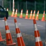 Auto jede po silnici lemované oranžovými dopravními kužely