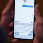 Detail rukou, které drží chytrý telefon a píšou zprávu