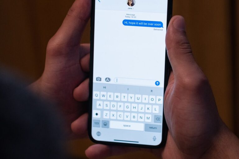 Detail rukou, které drží chytrý telefon a píšou zprávu