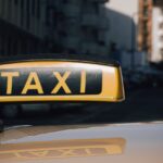 Detail střešní svítilny s nápisem TAXI na voze v městské ulici