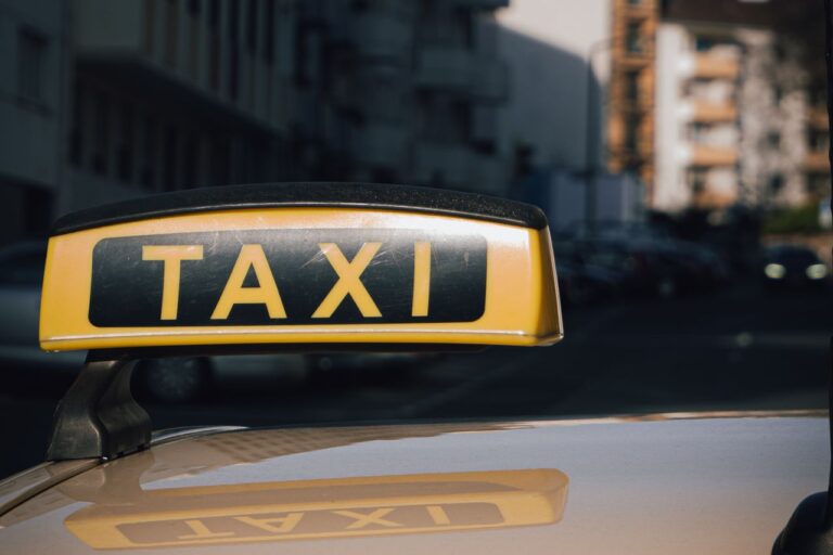 Detail střešní svítilny s nápisem TAXI na voze v městské ulici