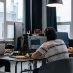 Několik lidí pracuje u počítačů vedle sebe v moderní kanceláři