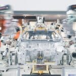 Robotická ramena montují karoserii auta na výrobní lince v automobilce