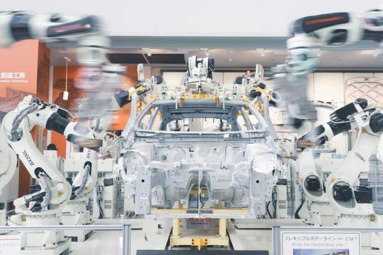 Robotická ramena montují karoserii auta na výrobní lince v automobilce